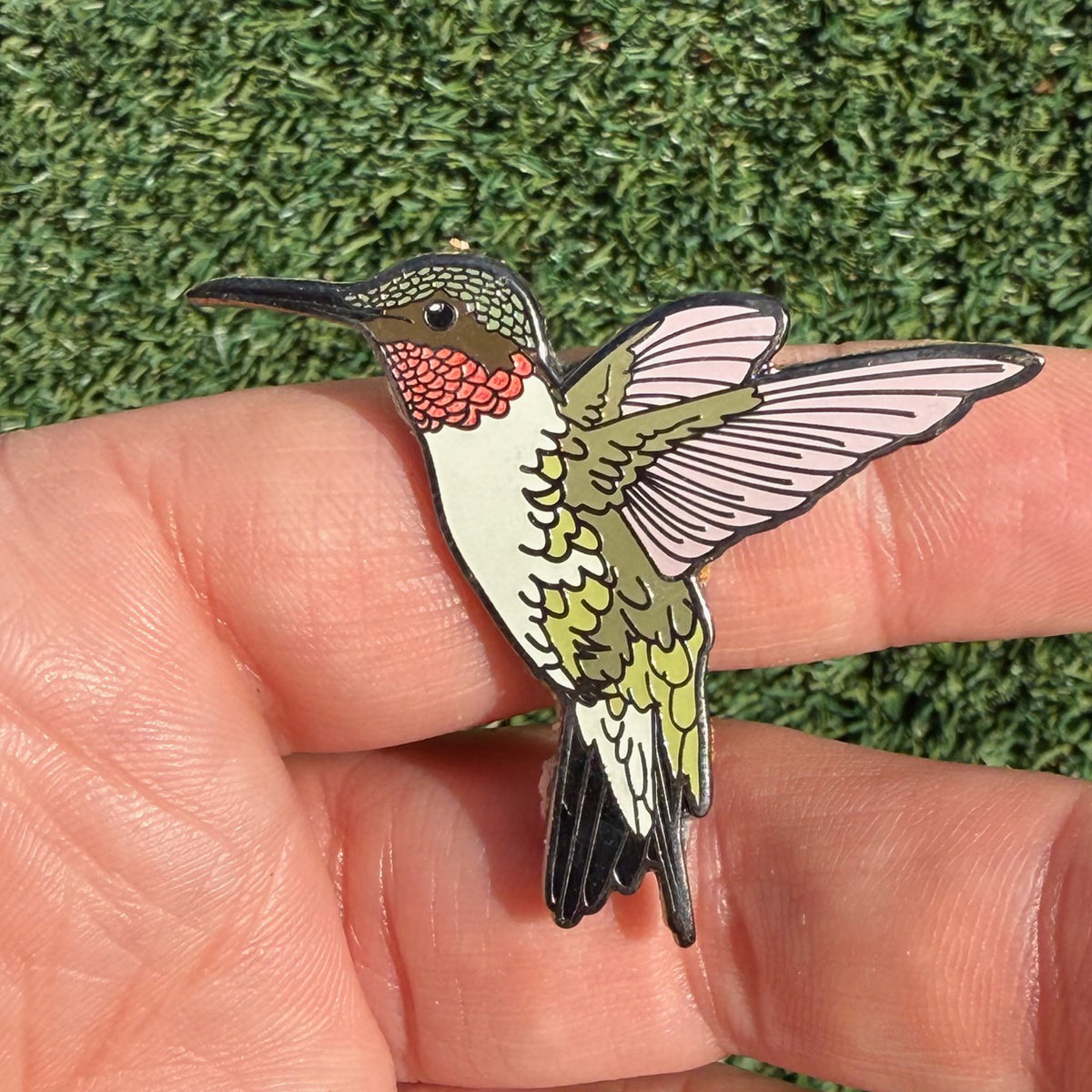 Ruby-throated Hummingbird glitter enamel pin shown in hand