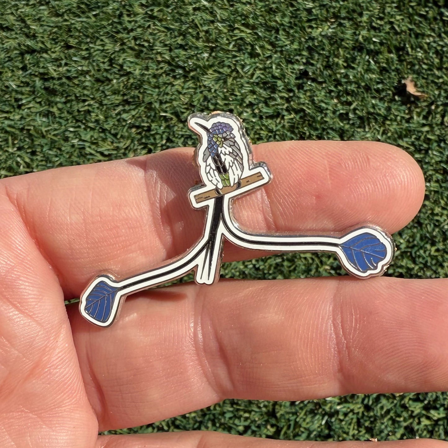 Marvelous Spatuletail enamel pin shown in hand