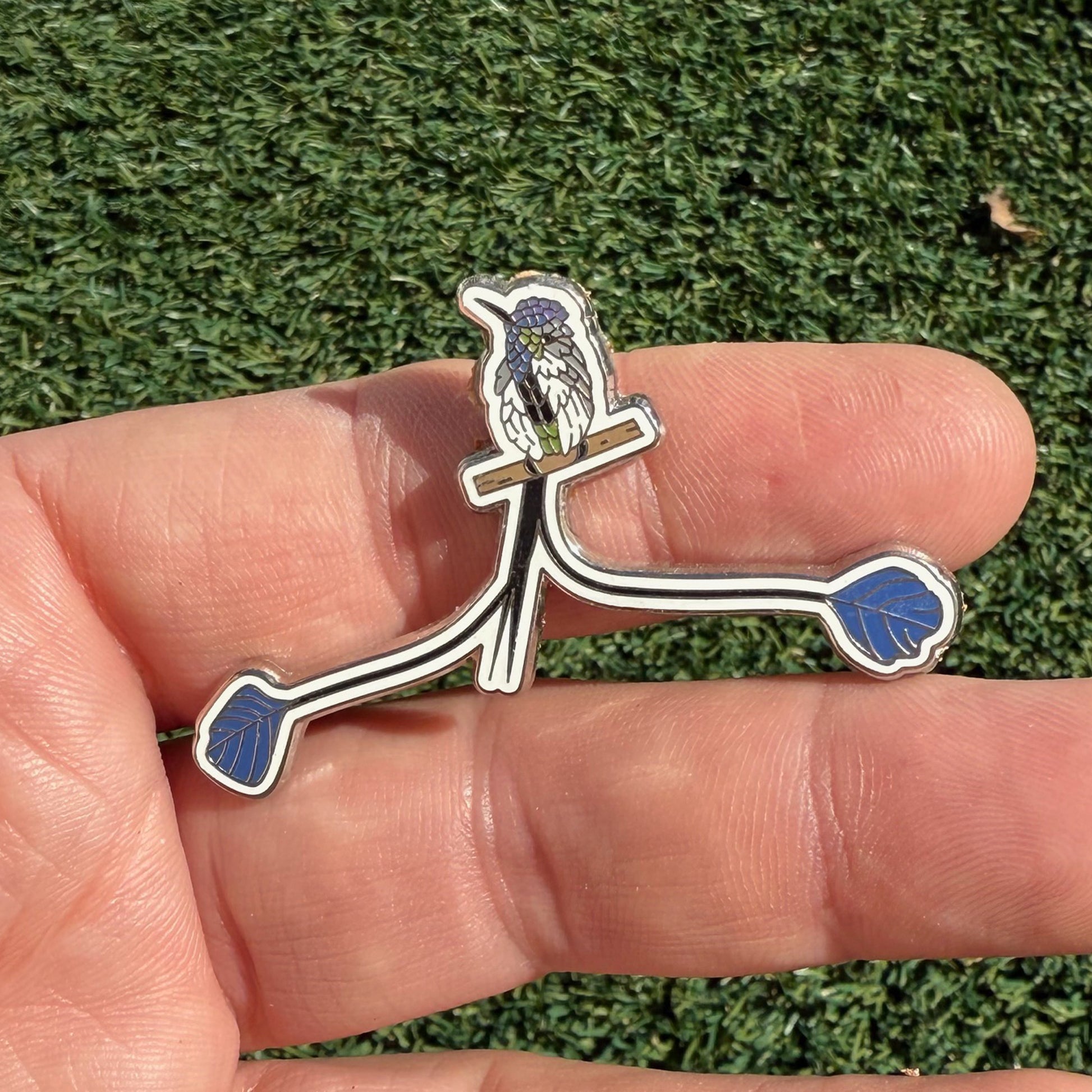 Marvelous Spatuletail enamel pin shown in hand
