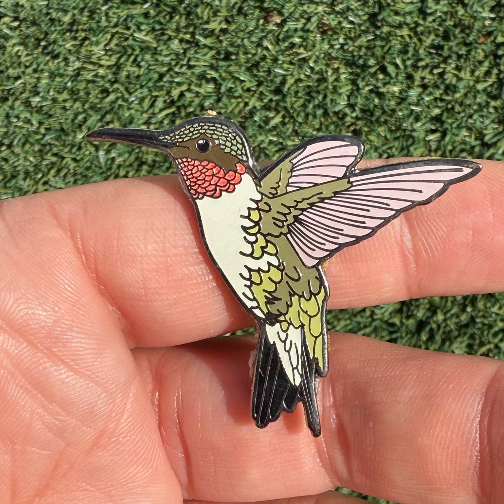 Ruby-throated Hummingbird glitter enamel pin shown in hand