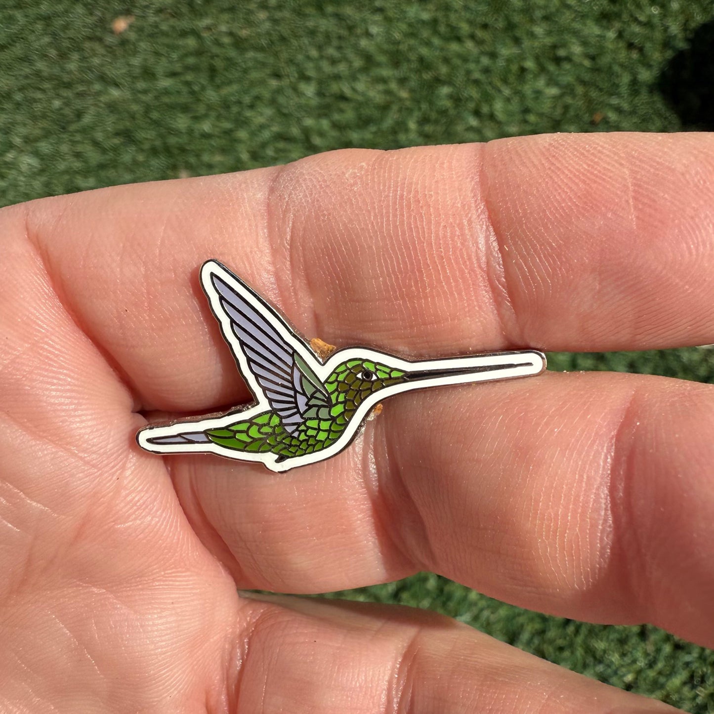 Sword-billed Hummingbird enamel pin shown in hand