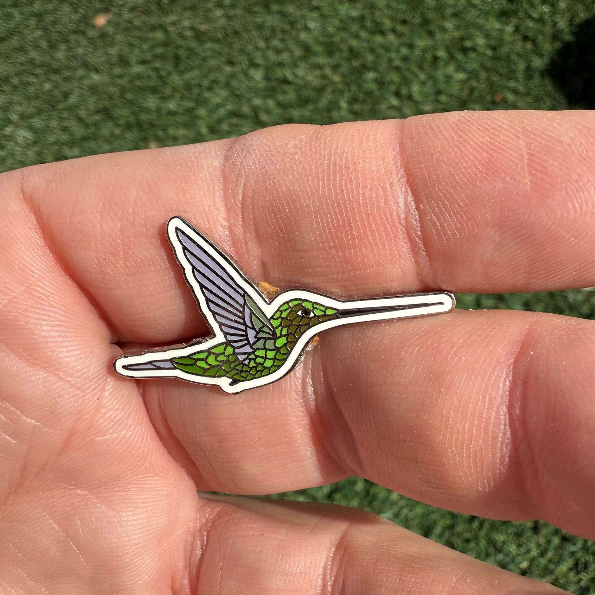 Sword-billed Hummingbird enamel pin shown in hand